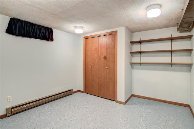 unfurnished bedroom with a textured ceiling, a baseboard heating unit, and a closet