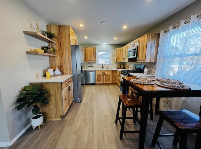 kitchen featuring light hardwood / wood-style flooring, backsplash, appliances with stainless steel finishes, and sink