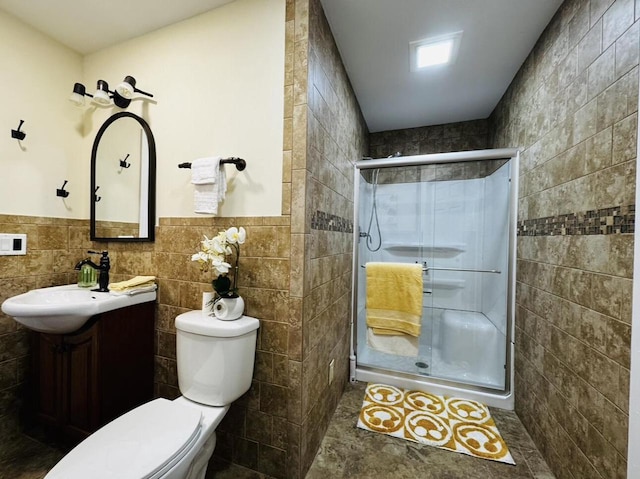 bathroom featuring tile walls, a shower with shower door, vanity, and toilet