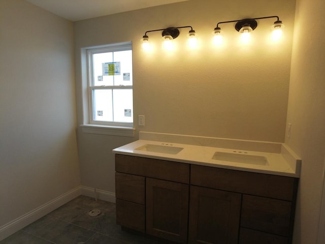 bathroom featuring baseboards, double vanity, a sink, and tile patterned floors