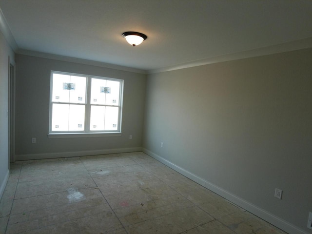 empty room featuring crown molding and baseboards