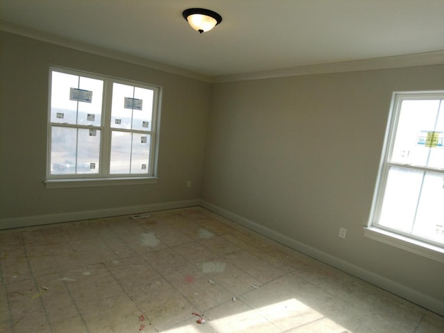 spare room with baseboards and crown molding