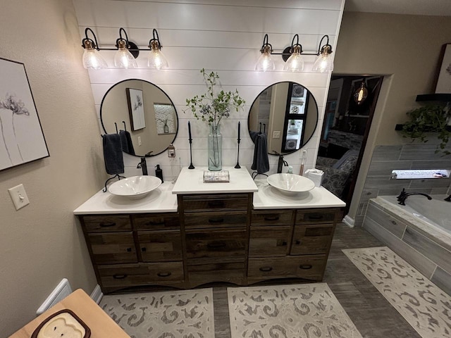 bathroom featuring vanity, hardwood / wood-style flooring, and tiled bath