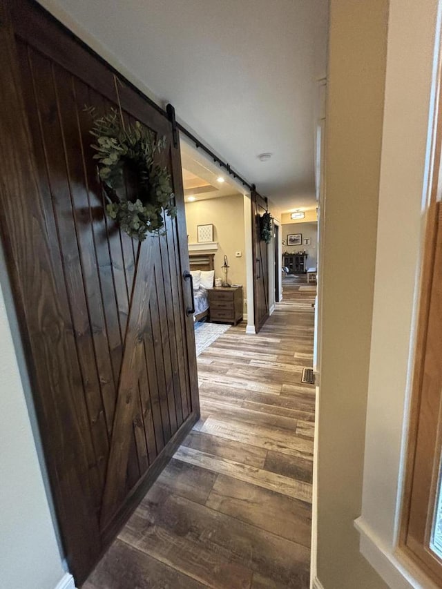 hallway with a barn door and wood-type flooring