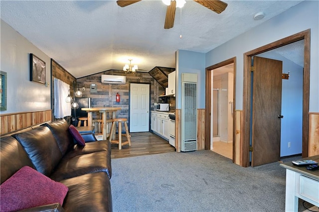 living room featuring ceiling fan, wood walls, dark colored carpet, vaulted ceiling, and a wall unit AC