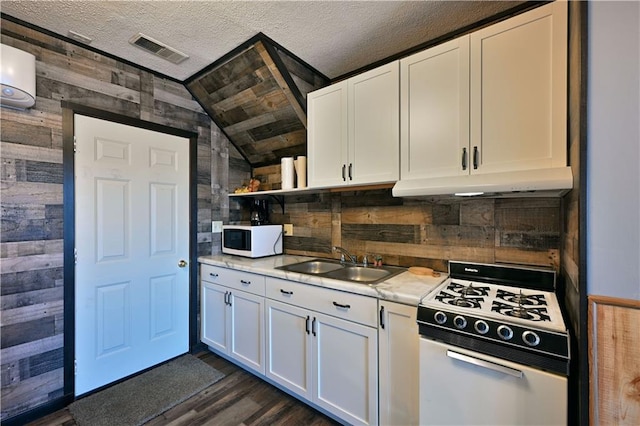 kitchen featuring white cabinets, lofted ceiling, wood walls, and white appliances