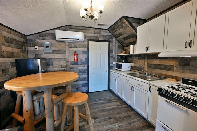 kitchen with dark wood-type flooring, white cabinets, white appliances, wood walls, and a wall mounted air conditioner