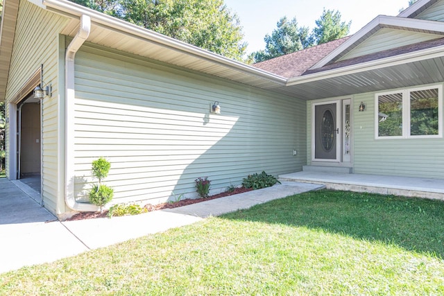 entrance to property featuring a lawn and a garage