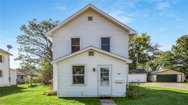 back of house featuring a garage, a yard, and an outbuilding