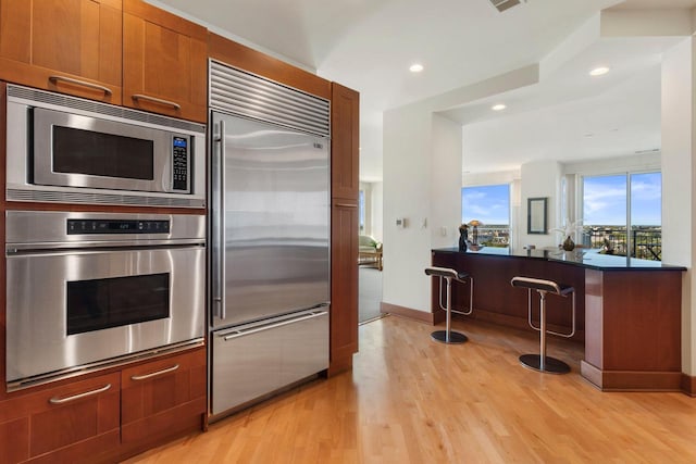 kitchen with built in appliances and light hardwood / wood-style floors