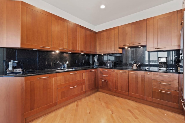 kitchen featuring dark stone countertops, light wood-type flooring, and backsplash