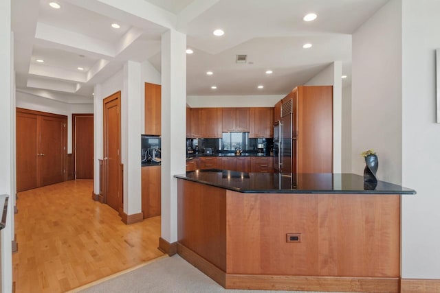 kitchen featuring stainless steel built in fridge, sink, kitchen peninsula, tasteful backsplash, and light hardwood / wood-style flooring