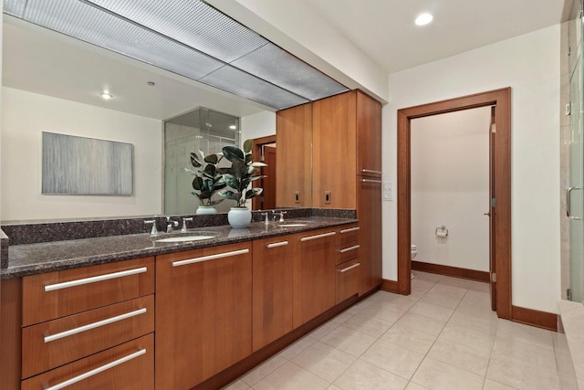 kitchen with dark stone counters, sink, and light tile patterned floors