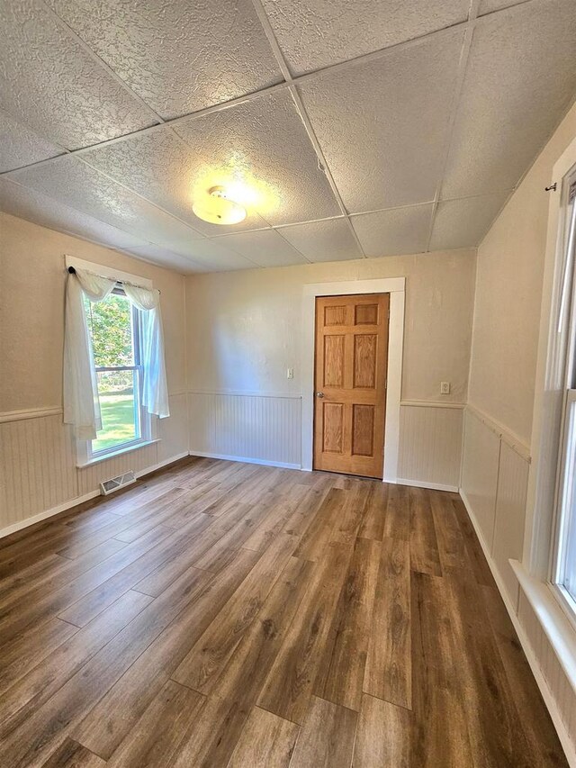 spare room with a wainscoted wall, wood finished floors, and visible vents