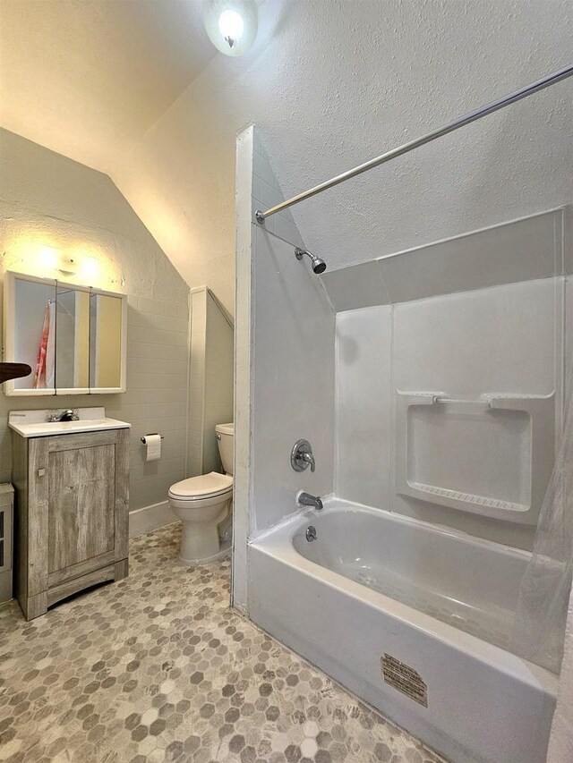 full bath with vanity, lofted ceiling, toilet, bathing tub / shower combination, and a textured ceiling