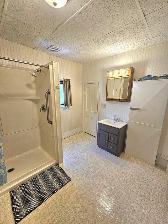 bathroom with visible vents, wood walls, vanity, a stall shower, and a paneled ceiling