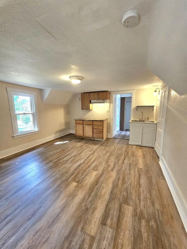 kitchen with open floor plan, dark wood-style flooring, baseboards, and a textured ceiling