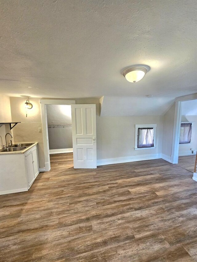 interior space featuring a sink, dark wood-style floors, baseboards, and a textured ceiling