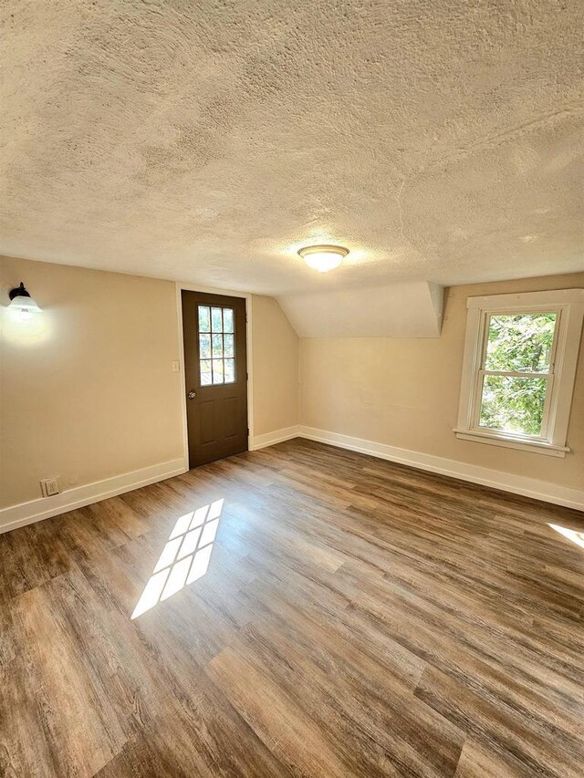 basement with a textured ceiling, baseboards, and wood finished floors