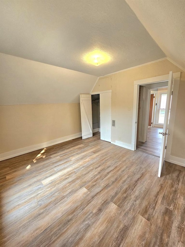 bonus room with vaulted ceiling, a textured ceiling, and hardwood / wood-style floors