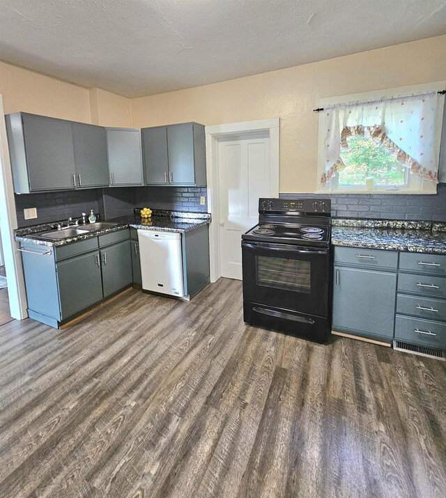 kitchen featuring dishwasher, dark wood-style floors, gray cabinetry, dark countertops, and black / electric stove