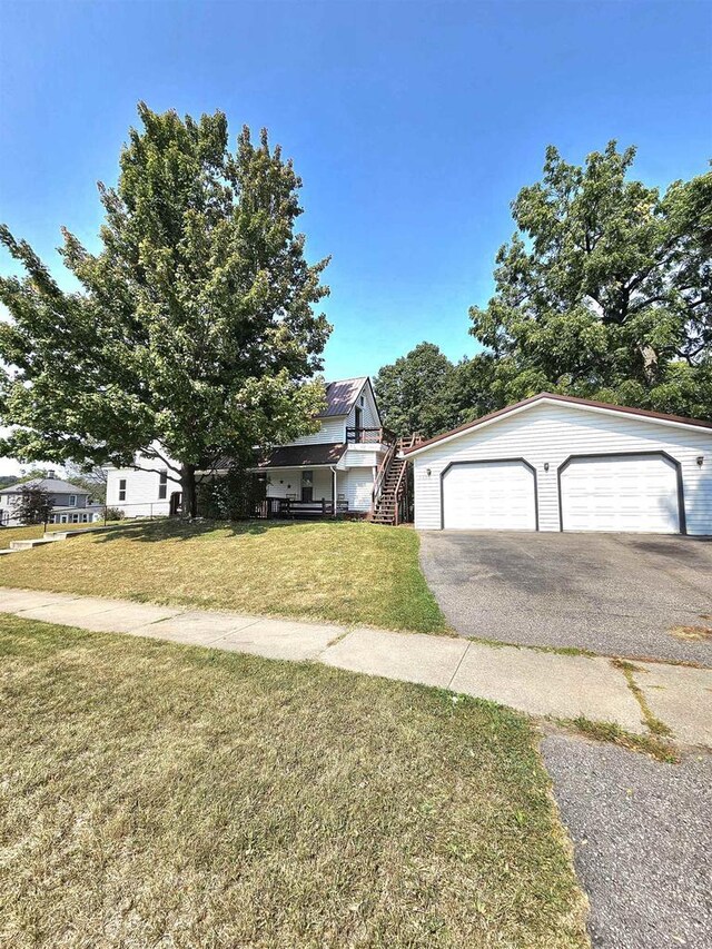 view of front of property featuring stairs, a garage, and a front yard