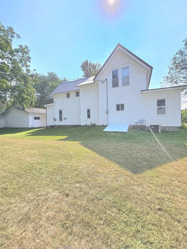 back of property with central AC unit and a yard