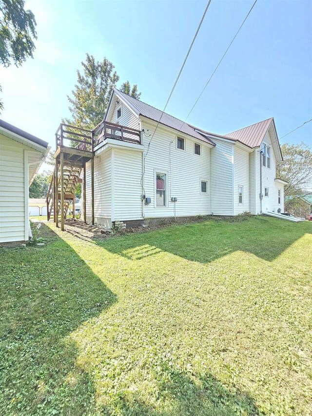 back of property with a lawn, metal roof, and stairway