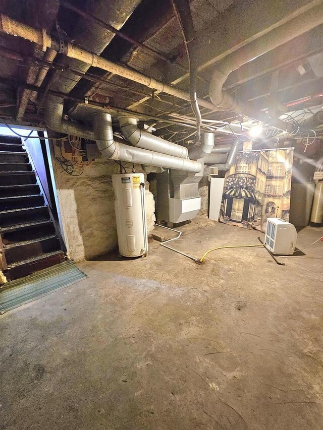 unfinished basement with heating unit, electric water heater, and stairway
