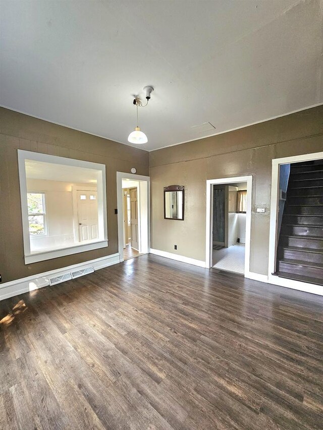 empty room with baseboards, stairway, and wood finished floors