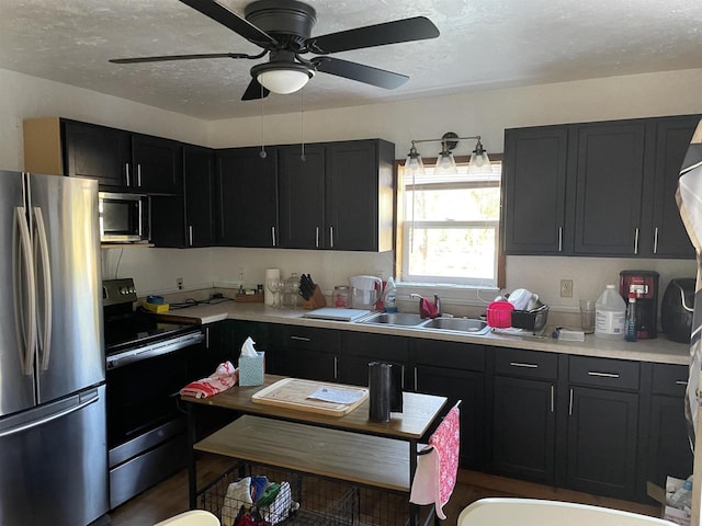 kitchen with a textured ceiling, sink, ceiling fan, and stainless steel appliances