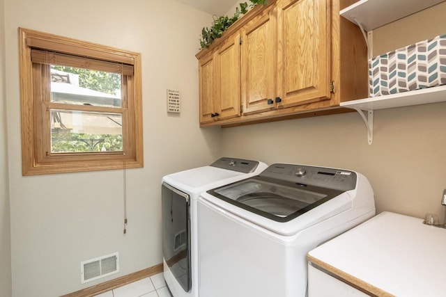 clothes washing area with cabinets, independent washer and dryer, and light tile patterned floors