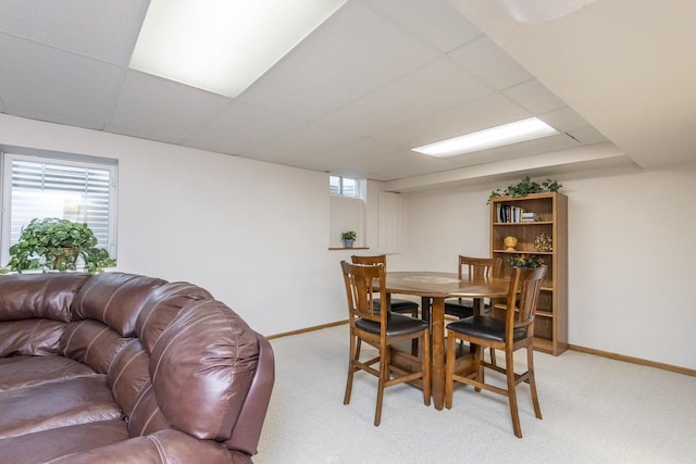 carpeted dining area with a paneled ceiling