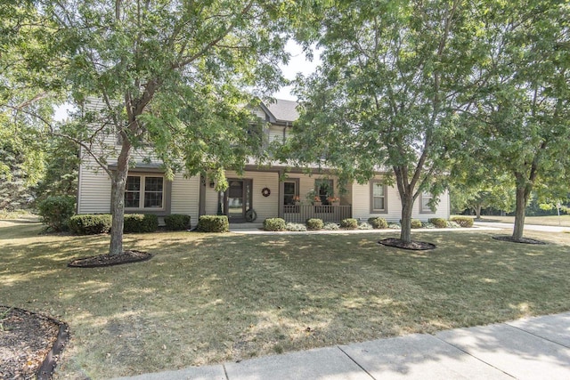 view of property hidden behind natural elements featuring a front yard and covered porch