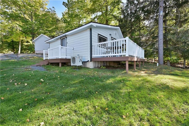 rear view of property featuring a lawn, ac unit, and a wooden deck