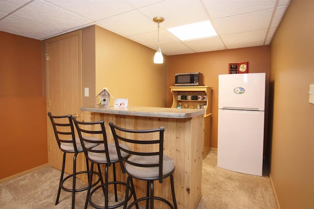 kitchen with kitchen peninsula, a breakfast bar area, light carpet, and white fridge