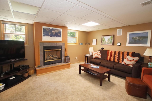 living room with carpet floors, a fireplace, and a drop ceiling