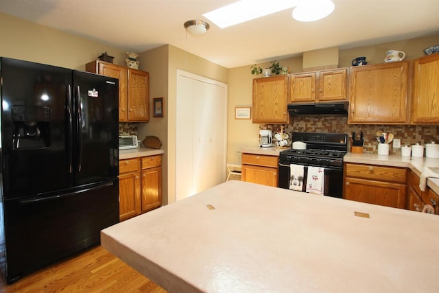 kitchen featuring light wood-type flooring, decorative backsplash, and black appliances