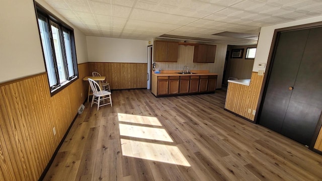 kitchen with wooden walls, light hardwood / wood-style floors, a paneled ceiling, and sink