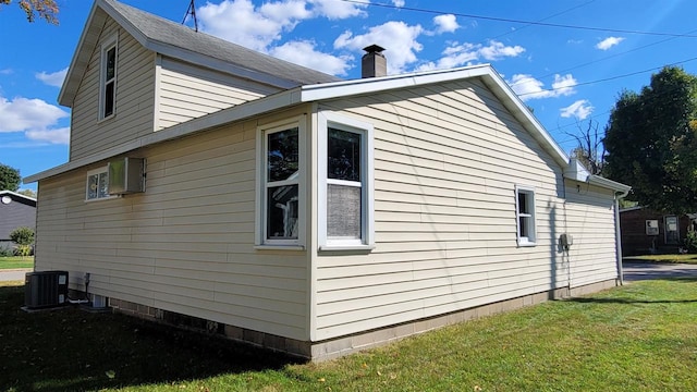 view of property exterior featuring a yard, central air condition unit, and a wall mounted air conditioner