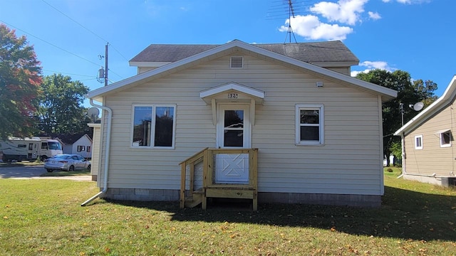 rear view of property featuring a lawn