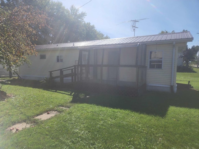 back of property featuring a sunroom and a yard