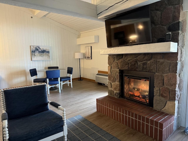 living room featuring a stone fireplace, beamed ceiling, and hardwood / wood-style flooring