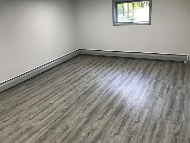 spare room with baseboard heating and dark hardwood / wood-style flooring