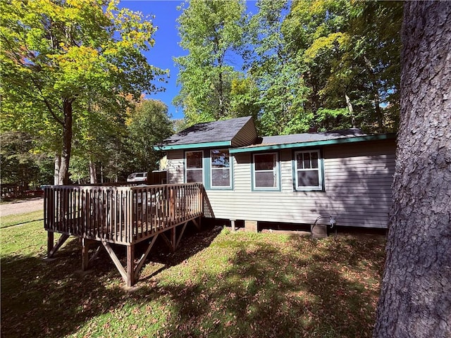 back of house with a deck and a lawn