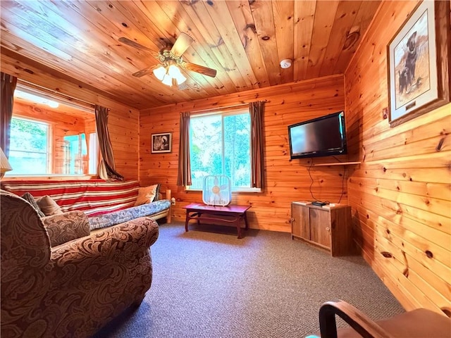 living room featuring wood ceiling, wooden walls, ceiling fan, and carpet floors