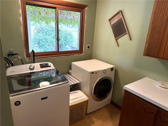 laundry room with washing machine and dryer, light hardwood / wood-style flooring, and cabinets