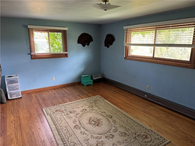 unfurnished room with baseboard heating and hardwood / wood-style flooring