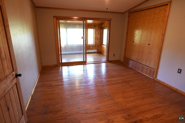 spare room with a baseboard radiator, wood-type flooring, and crown molding