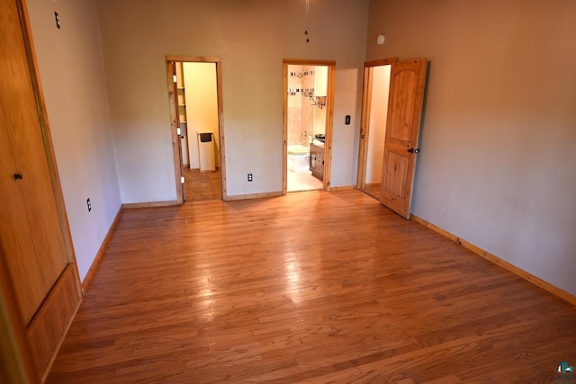 unfurnished bedroom with light wood-type flooring and ensuite bathroom